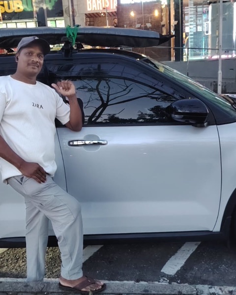 Mubarak, le chauffeur de Muba Taxi Service, à côté de sa voiture