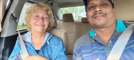 Un passager souriant assis à l'avant avec Mubarak dans la voiture de Muba Taxi Service